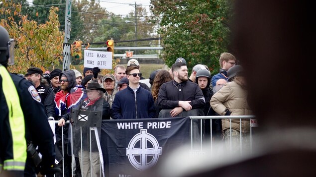 Des manifestants derrière une barricade sur laquelle on y voit une banderole où il est écrit «White Pride».