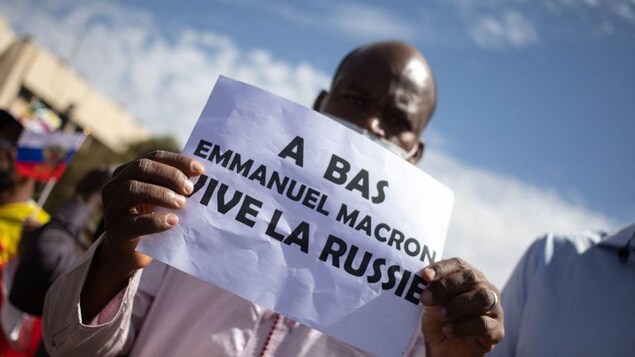 Un homme brandit une pancarte « À bas Emmanuel Macron, vive la Russie" lors d'une manifestation de masse à Bamako, le 14 janvier 2022.
