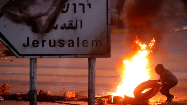 Un manifestant jette un pneu dans une barricade en feu, près de la ville de Ramallah, en Cisjordanie. Un manifestant jette un pneu dans une barricade en feu, près de la ville de Ramallah, en Cisjordanie.