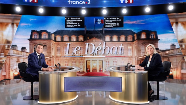 Emmanuel Macron et Marine Le Pen sont assis à deux tables opposées dans un studio télé avant de participer à un débat télévisé.