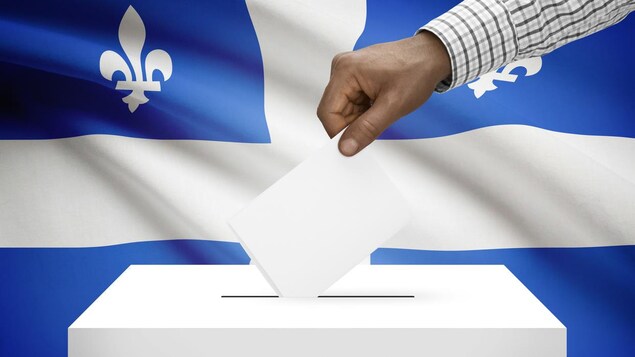Une main qui dépose un bulletin de vote dans une boite de scrutin sur fond de drapeau québécois
