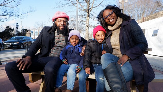 Une famille afro-américaine assis sur un banc à l'extérieur.