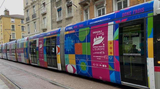 Des voitures du tramway de Grenoble arborent de vives couleurs pour attirer le regard sur un slogan qui indique fièrement que l’on se trouve dans la Capitale Verte de l’Europe 2022.