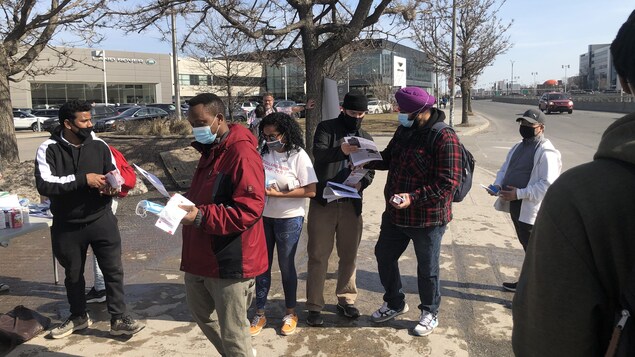 Des personnes rassemblés à l'extérieur, certains distribuant des pamphlets.