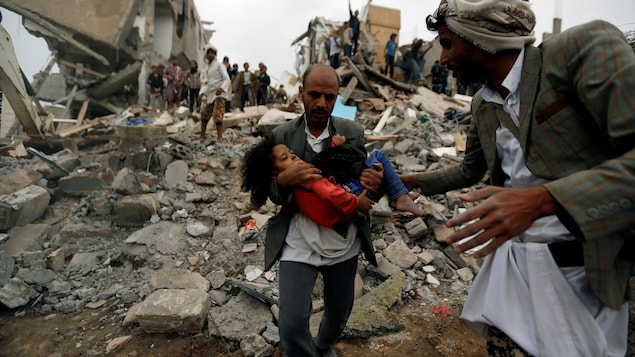 Un homme porte une fillette dans ses bras dans les décombres d'un bâtiment. Un homme porte une fillette dans ses bras dans les décombres d'un bâtiment.
