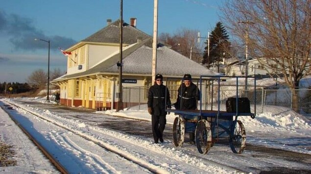 Une femme et un homme, l'hiver, près d'une gare.