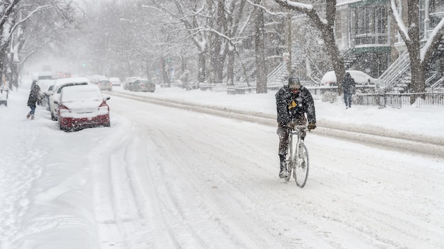 Un homme fait du vélo l'hiver à Montréal.