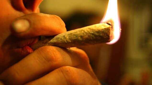 Un jeune fume un joint.