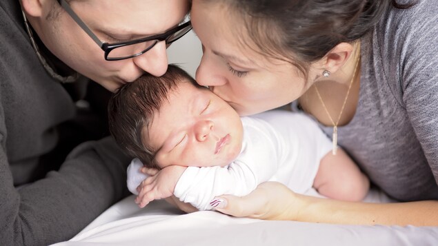 Des parents embrassent leur nouveau-né.
