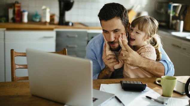Un père et sa fille s'amusent devant un ordinateur.
