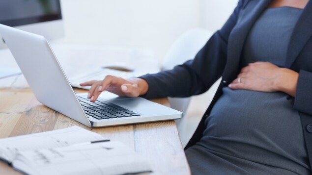 Une femme enceinte est devant son ordinateur au travail.