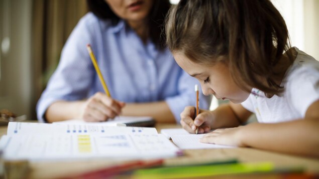 Une femme aidant un enfant à faire ses devoirs.