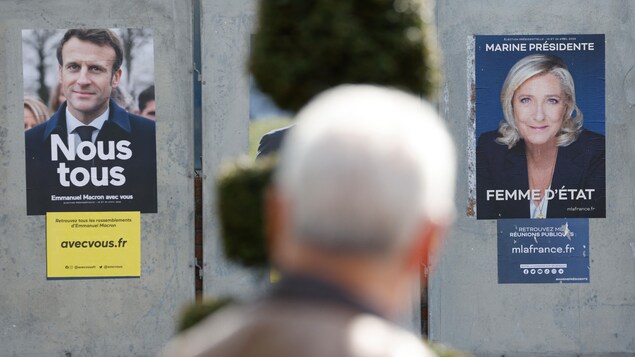 Un homme passe devant les affiches de campagne du président sortant Emmanuel Macron et de la candidate du Rassemblement national Marine Le Pen à Denain, le 11 avril 2022. 