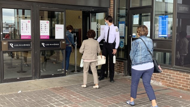 Des personnes entrent dans un centre commercial.