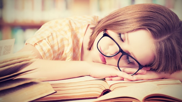 Une étudiante dort sur ses livres d'école.