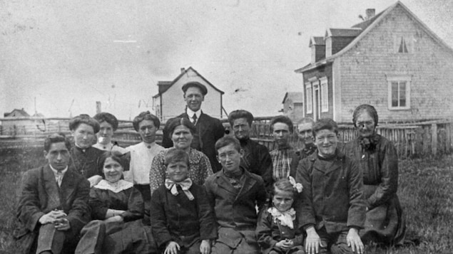 Famille d’Hyppolite Turbis et de Marie Delvie Thériault de Havre-Saint-Pierre, vers 1923, dehors (15 personnes agenouillées sur l'herbe).