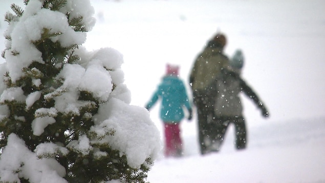 Un père et ses deux enfants dans la neige.