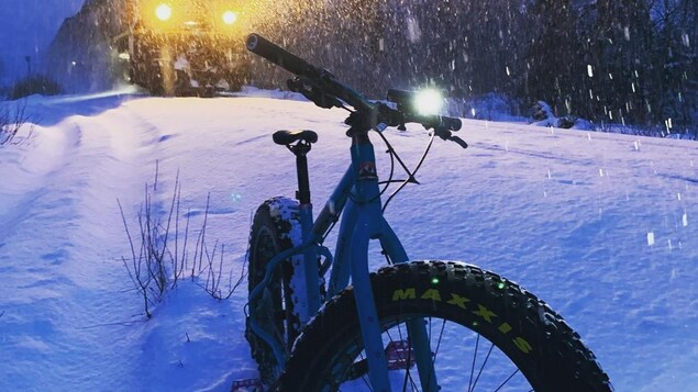 Un fat bike dans la neige, devant un train qui passe.