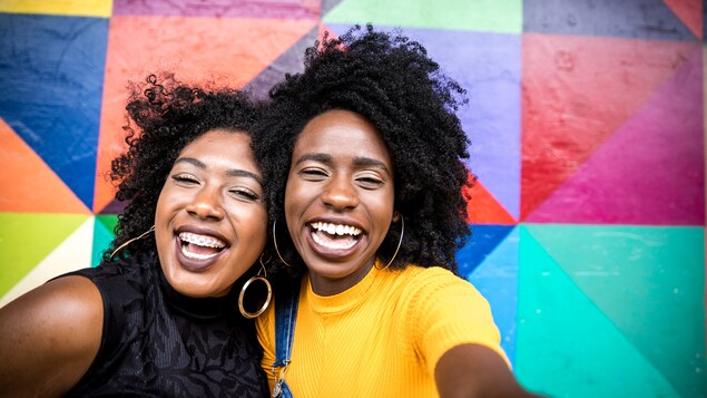 Deux femmes noires sourient à l'objectif, elles prennent une photo en mode selfie