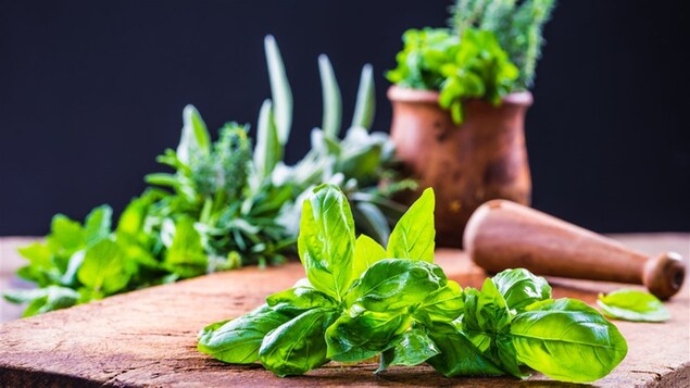 Des fines herbes sur une planche à côté d'un pilon
