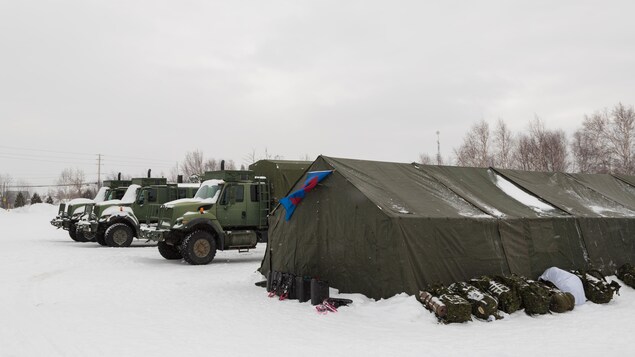 Un grande tente aux côtés de trois camions de l'armée canadienne.