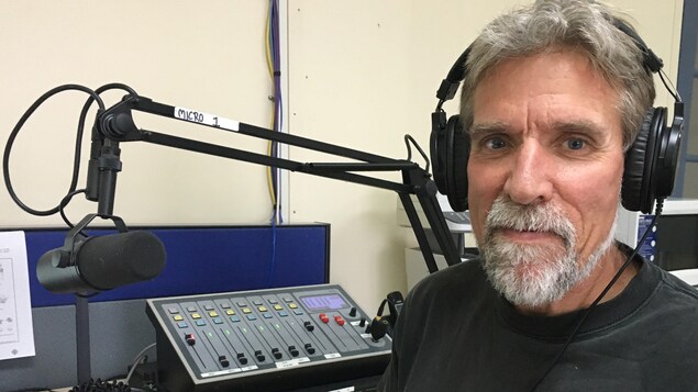 Le journaliste gaspésien Gilles Gagné, chroniqueur à l'émission Au coeur du monde, devant le micro du studio de Radio-Canada à Carleton-sur-Mer.