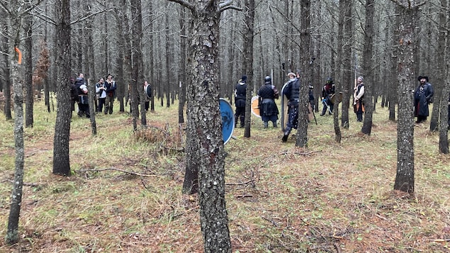 Une vingtaine de joueurs portant armure et bouclier se placent en deux équipes dans une plantation.