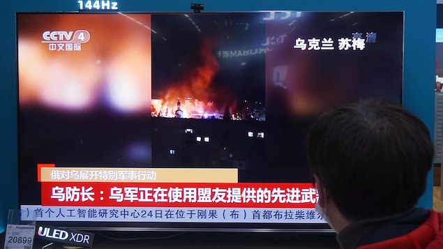 Un habitant regarde un écran de télévision diffusant des informations sur le conflit entre la Russie et l'Ukraine dans un centre commercial à Hangzhou, dans la province orientale du Zhejiang, en Chine, le 25 février 2022.