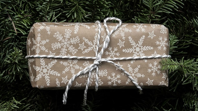 Un cadeau emballé déposé sur des banches de sapin.