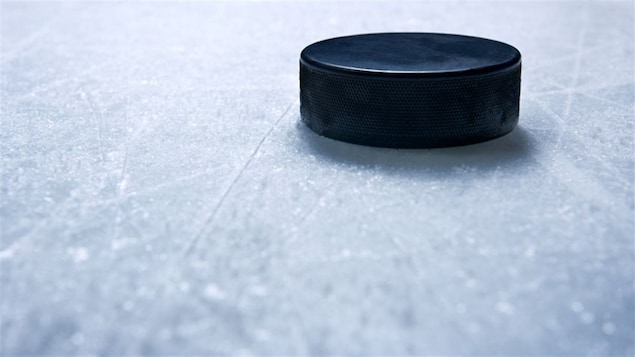 Une rondelle de hockey en gros-plan sur la glace d'un patinoire.