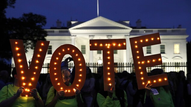 Des électeurs américains tiennent les lettres qui forment le mot « vote » devant la Maison-Blanche.