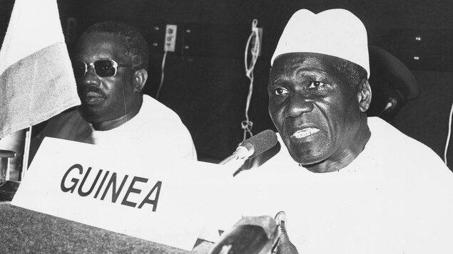 Sékou Touré parle lors d'une conférence. Un homme se trouve assis à sa droite.