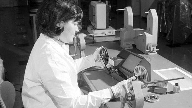 Une technicienne utilise un projecteur de cinéma.