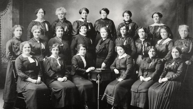 Photo ancienne en noir et blanc d'un groupe d'une vingtaine de femmes en vêtements d'époque. Photo ancienne en noir et blanc d'un groupe d'une vingtaine de femmes en vêtements d'époque.