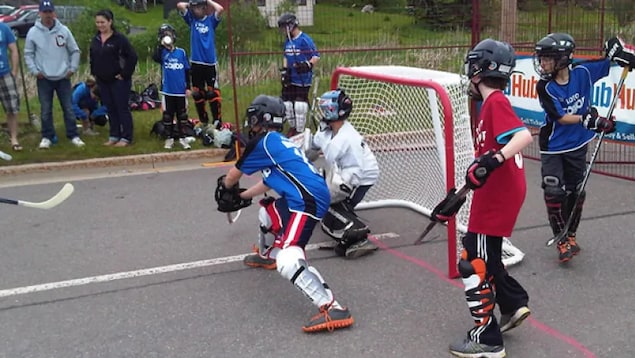 Des enfants jouent au hockey dans la rue.