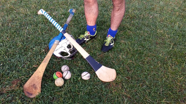 Des balles, des bâtons, un casque et un joueur de hurling sur le gazon