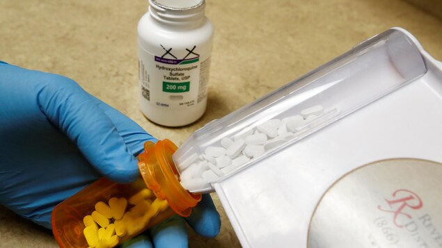 Un chercheur place des pilules d'hydroxychloroquine dans un contenant.