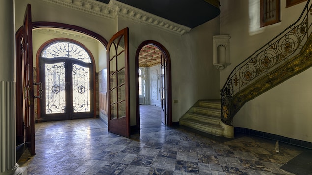 Une entrée de maison lumineuse avec de grandes portes vitrées et des sculptures de fer.