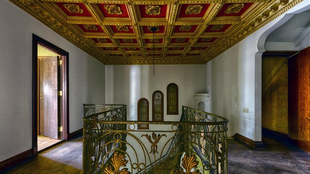 L'intérieur d'une maison luxueuse avec des caissons sculptés rouge et or au plafond.