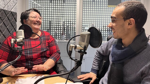 Deux personnes rient entre elles dans un studio de radio.