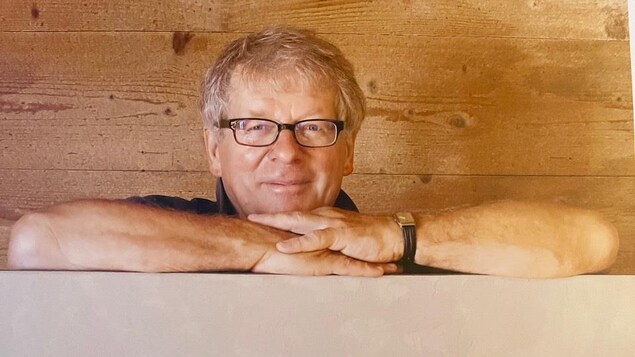 Un homme est photographié avec le tableau d'un artiste.