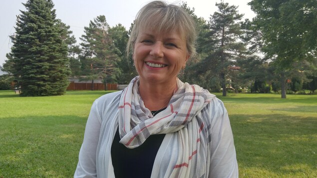 Joan Simard à l'extérieur devant des arbres.