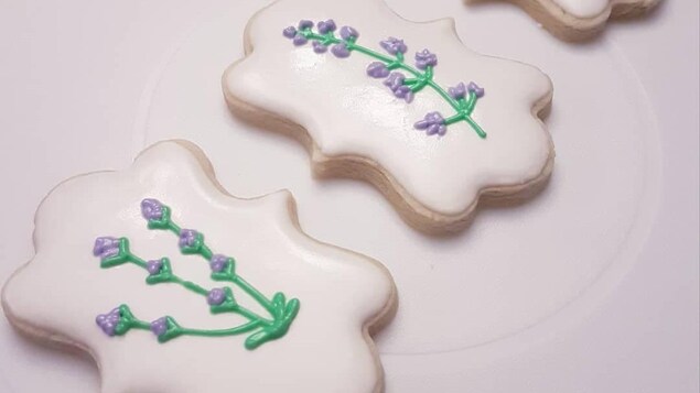 Trois biscuits décorés de fleurs sur une assiette.