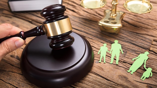 Un juge frappe son maillet près d'une représentation en papier d'une famille séparée et d'une balance.