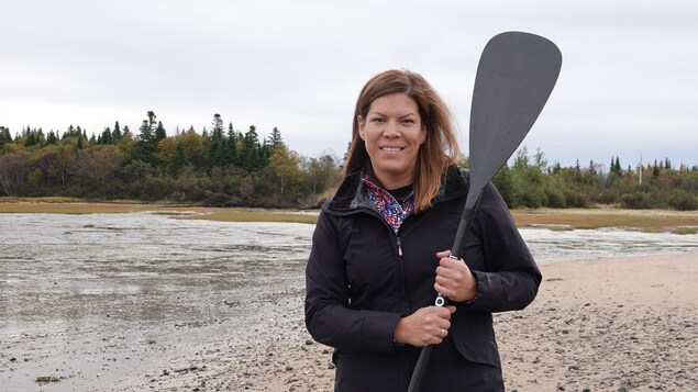 Kateri Champagne Jourdain avec une planche à pagaie à la plage. 