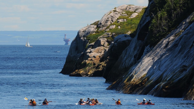 Des kayakistes sur l'eau, près de gros rochers.
