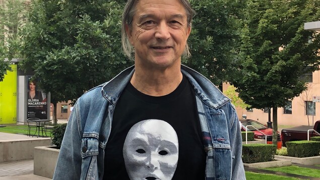 Un homme portant un t-shirt avec un masque qui représente un visage.