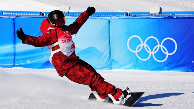 Une athlète canadienne célèbre sur sa planche à neige en levant les bras.