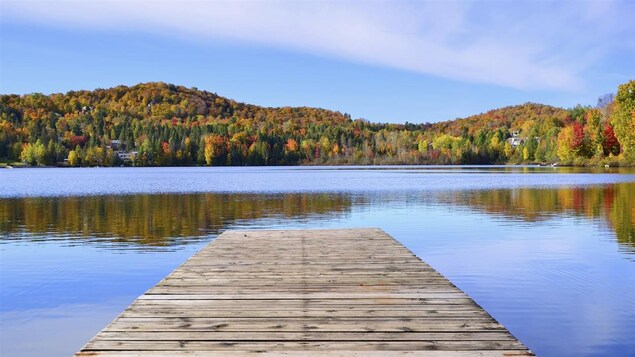 Photo d'un quai sur un lac avec les arbres tout en couleurs.
