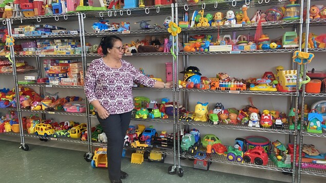 L’intervenante de la joujouthèque Fouzia Khomani devant des étagères de jouets.